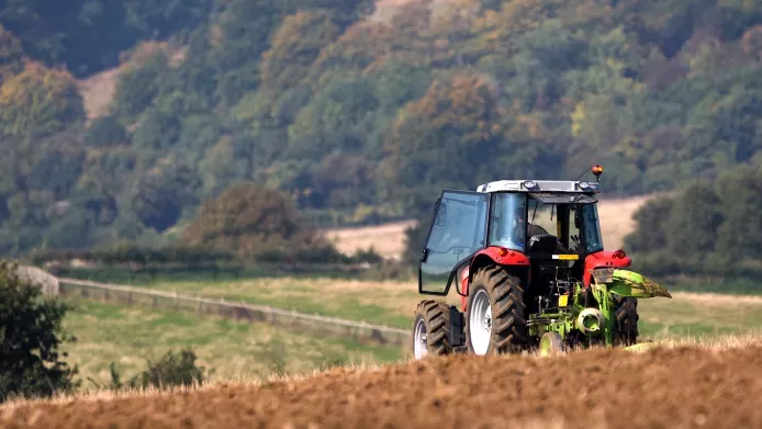 A tractor ploughing a field in front of some hills