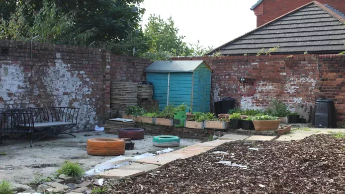 The transformed garden at conquer life, free of rubbish with planters and a seating area
